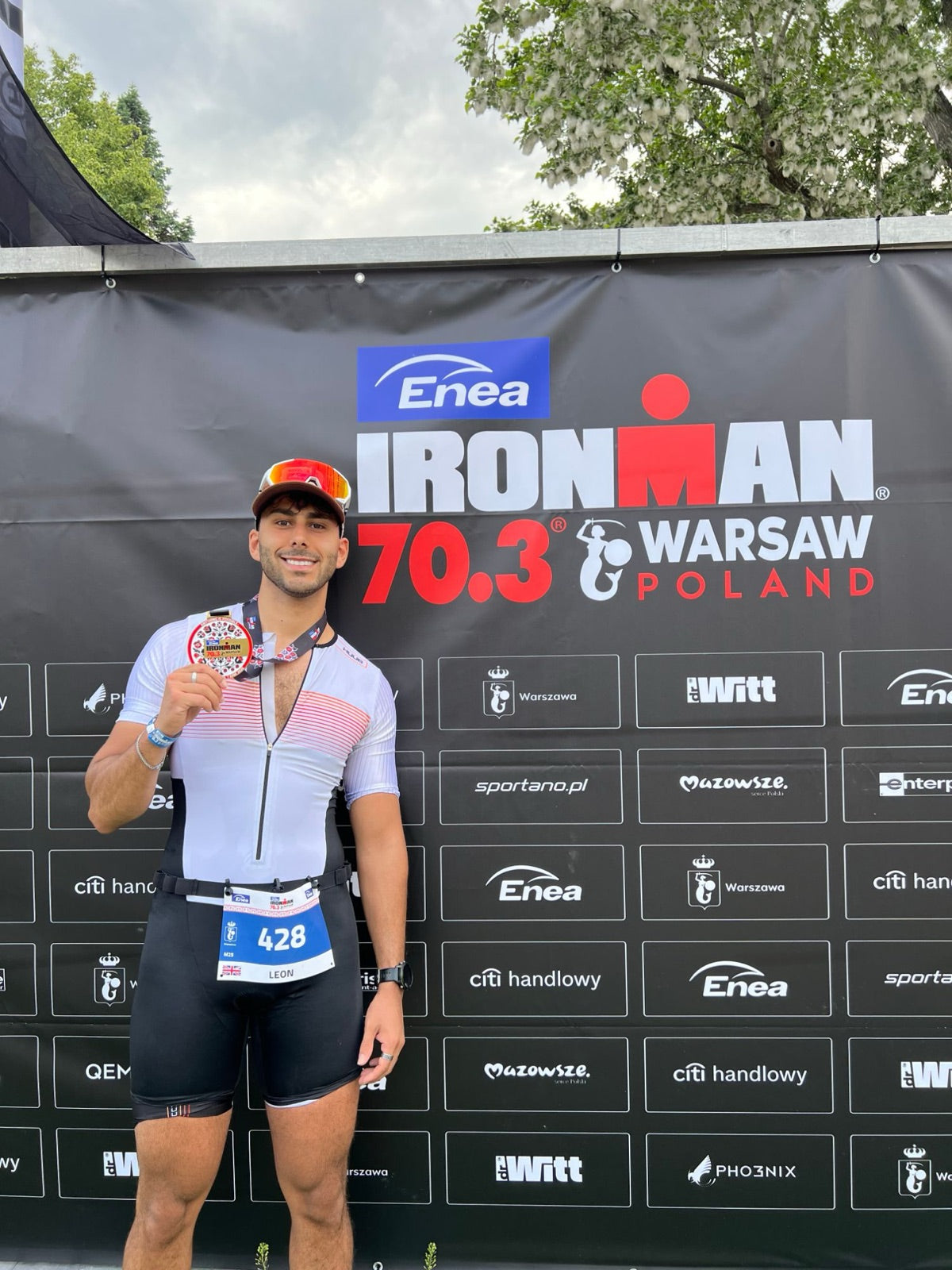 Leon, founder of VitaVera, holding his finisher medal after an Ironman 70.3 triathlon